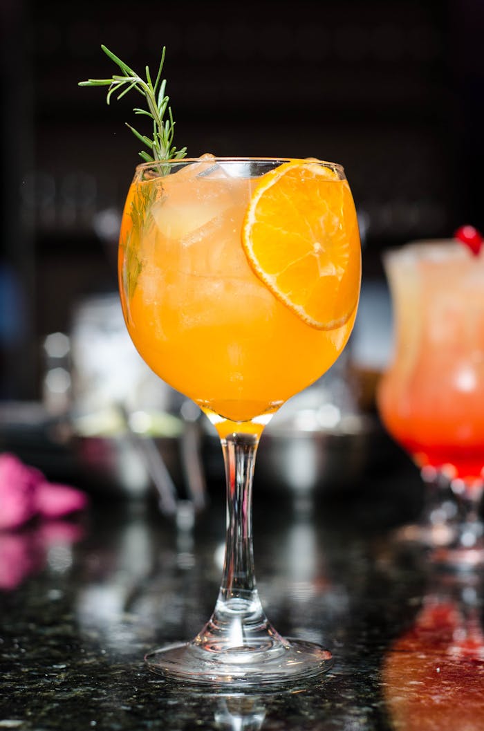 footer-cta Refreshing orange cocktail with ice, garnished with rosemary and orange slice. Perfect for summer parties.