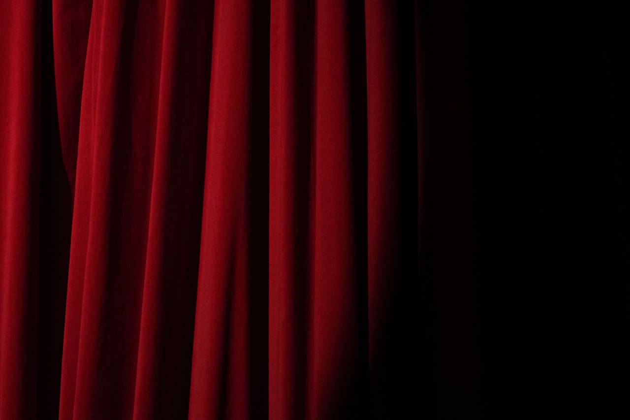 home-hero Elegant red velvet curtain with dramatic lighting perfect for theater themes.